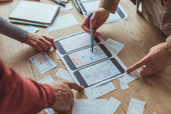 cropped-view-of-designers-working-with-app-sketches-and-template-of-mobile-website-at-table.jpg